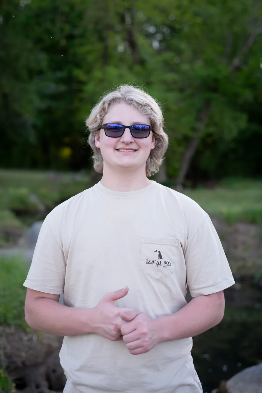 Caleb Whitfield, owner of Whitfield Visuals, outdoors by a creek
