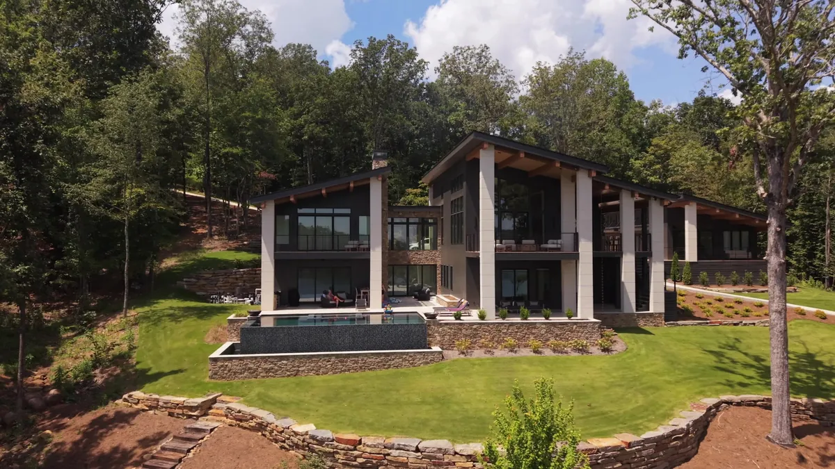 Rear elevation of a modern lake house with infinity pool and stone terraces
