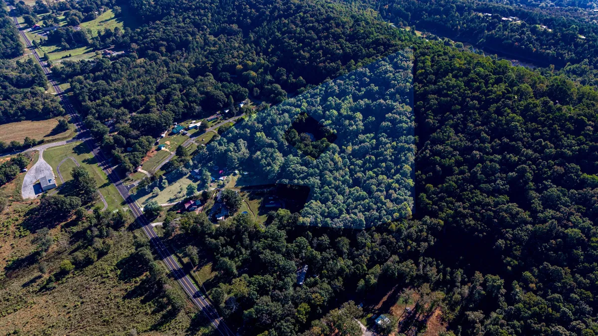 Aerial view of wooded acreage with the approximate property outline highlighted